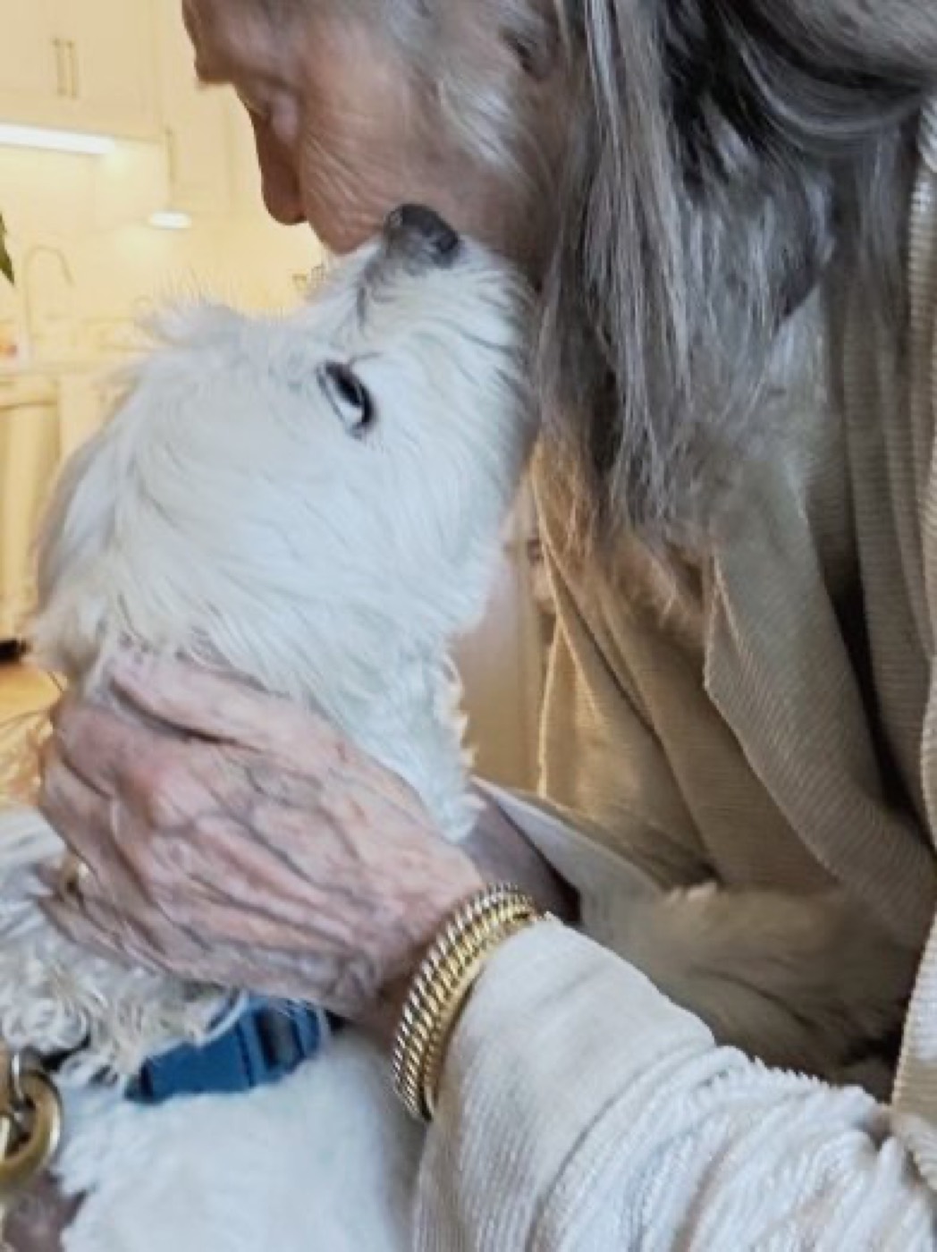 A resident leaning in for a forehead kiss with a fluffy dog.